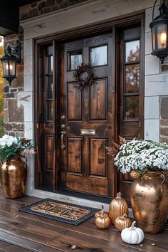 the front porch is decorated with gold and white flowers, pumpkins, and urns