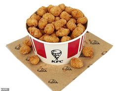 a bowl filled with fried food sitting on top of a napkin next to a cup