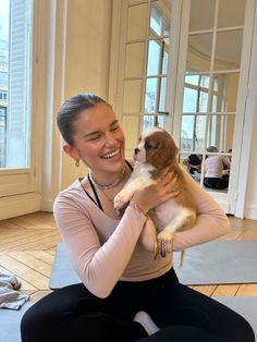 a woman sitting on the floor holding a puppy