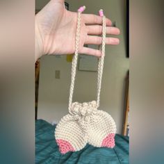 a hand is holding an object made out of crocheted yarn and pink trims