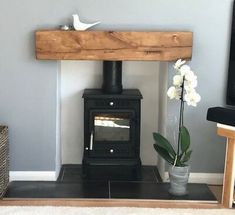 a wood burning stove sitting in a living room next to a vase filled with flowers