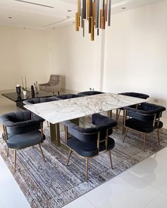 a marble dining table surrounded by blue velvet chairs and gold chandelier hanging from the ceiling