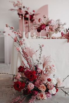 a table with flowers and candles on it, next to a white cloth covered tablecloth