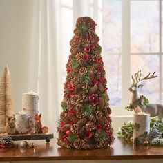 a christmas tree made out of pine cones on a table next to other holiday decorations