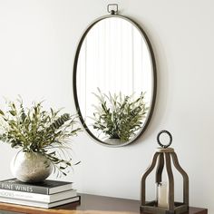 a wooden table topped with a mirror and vase filled with plants on top of it