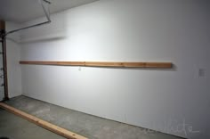 an empty room with white walls and wooden shelfs on the wall next to it