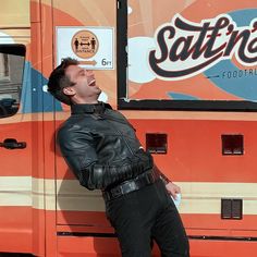 a man leaning against the side of a food truck