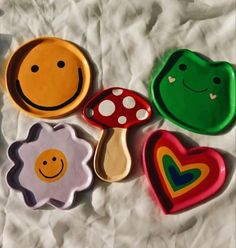 four different shaped cookies sitting on top of a white sheet with mushrooms, hearts, and smiling faces