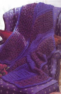 a purple crocheted blanket sitting on top of a chair