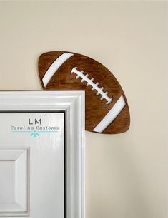 a wooden football hanging on the wall next to a white frame