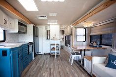 the interior of an rv with wood flooring and blue accents on the kitchen counter