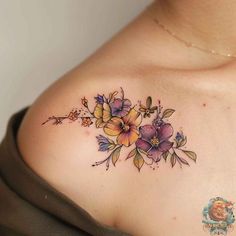 a woman's chest with flowers and leaves tattooed on the top of her shoulder