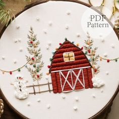 a red barn with white snowflakes and trees on it is featured in this hand embroidery pattern