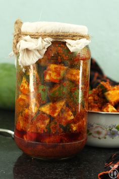 a glass jar filled with food sitting on top of a table next to a bowl