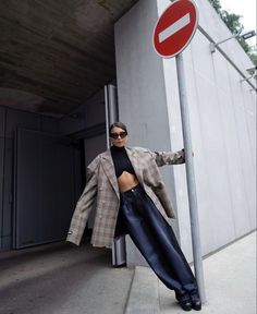 a woman leaning up against a pole with a no entry sign in front of her