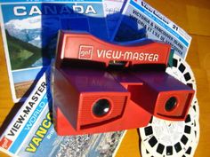 a red camera sitting on top of a wooden table next to some magazines and other items