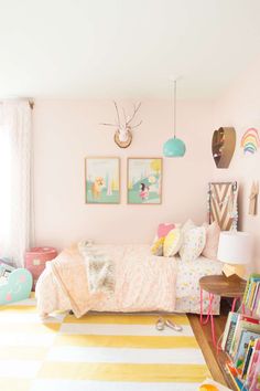 a child's bedroom decorated in pastel colors and striped rugs with pictures on the wall