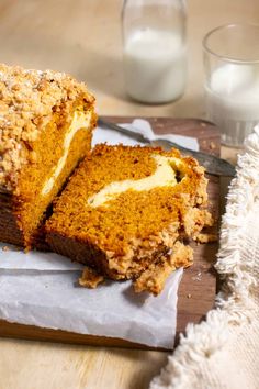 a loaf of cake sitting on top of a cutting board next to a glass of milk