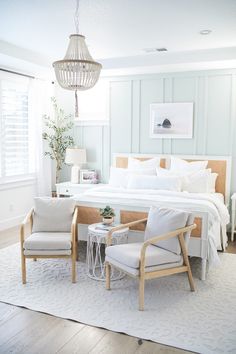 a bedroom with a bed, two chairs and a chandelier hanging from the ceiling