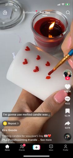 someone is painting hearts on a small piece of soap with a candle in the background