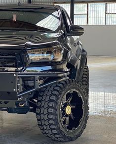 the front end of a black truck with large tires on it's rims