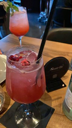 a glass filled with pink liquid sitting on top of a wooden table