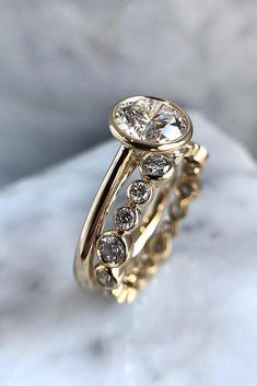 a close up view of a gold ring with diamonds on it, sitting on a marble surface