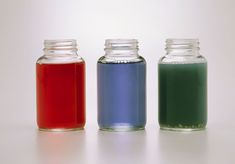 three jars filled with liquid sitting on top of a table