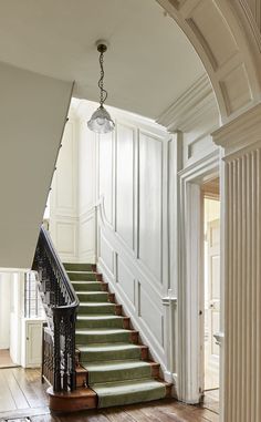 a staircase with green carpet and white walls