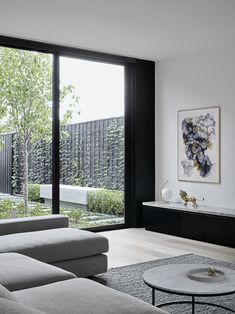 a living room filled with furniture next to a large glass window covered in greenery