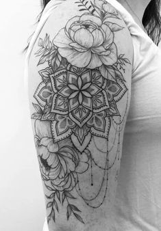 a woman's shoulder tattoo with flowers and leaves on the back of her arm