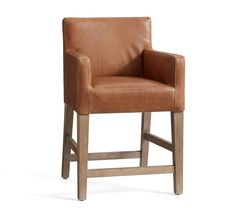 a brown leather bar stool with wooden legs and armrests on an isolated white background