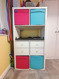 an entertainment center with multicolored bins and drawers in a child's room