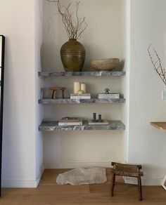 a room with some shelves filled with books and vases