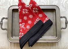 two red and black napkins sitting on top of a metal tray