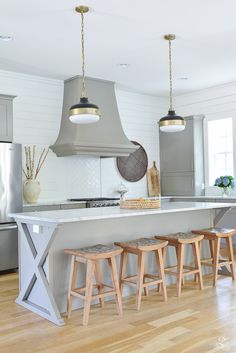 a kitchen island with stools in front of it and lights hanging from the ceiling