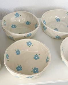 four white bowls with blue flowers on them