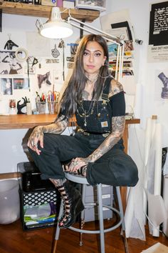 a tattooed woman sitting on top of a stool