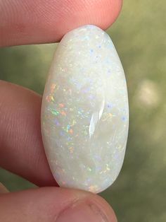 a person holding a white opal in their hand