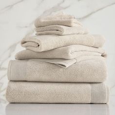 towels stacked on top of each other in front of a white marble wall and floor