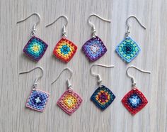 six crocheted square shaped earrings are displayed on a wooden surface with silver earwires