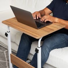 a person sitting on a couch using a laptop computer at a table in front of them