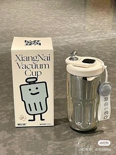 a glass cup next to a cardboard box on the floor with a sticker that says xing - nai vacuum cup