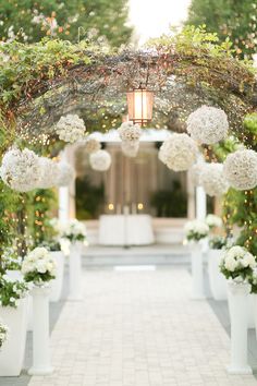 an outdoor ceremony with white flowers and greenery