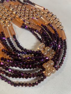 Why You'll Love It: Striking Design: The rich purple crystal glass beads paired with the warm golden sandy brown accents create a luxurious and timeless aesthetic. Premium Quality: Crafted with high-quality glass beads, ensuring durability and lasting brilliance. Comfortable Fit: The elastic design offers a comfortable and flexible fit for all-day wear. Versatile Style: Perfect for everyday wear, special occasions, or as a thoughtful gift. Cultural Significance: Purple: In Ivorian culture, purple symbolizes royalty, wisdom, and spirituality. The purple beads in the Lakota Waist Bead embody these qualities, adding a regal touch to your style. Golden Sandy Brown: Representing warmth, stability, and connection to the earth, the golden sandy brown accents bring a grounded elegance to the desig Elegant Brown Beaded Bracelets With Polished Beads, Elegant Brown Beaded Bracelet With Polished Beads, Elegant Brown Polished Beaded Bracelets, Elegant Multi-strand Brown Beads, Brown Faceted Beads Jewelry For Party, Gold Crystal Beaded Necklaces With Round Beads, Gold Beaded Amethyst Bracelets, Gold Crystal Beaded Necklace With Round Beads, Elegant Brown Multi-strand Beads