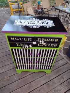 a green and black cabinet sitting on top of a wooden deck next to tables with chairs