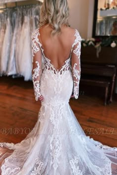 a woman in a wedding dress looking back at the bride's gown on display