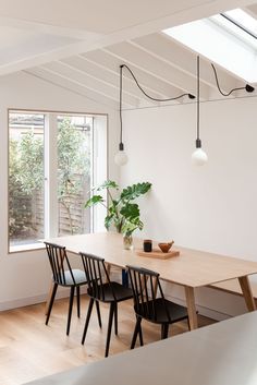 a dining room table with four chairs and a potted plant on the table next to it