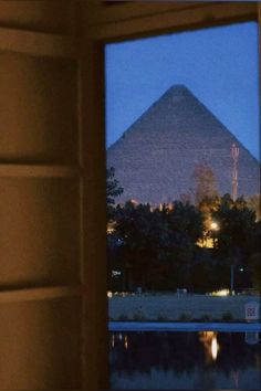 an open window with the view of a large pyramid in the background at night time