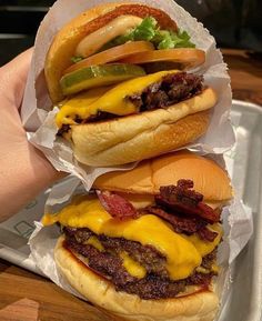 two hamburgers with cheese and pickles on them